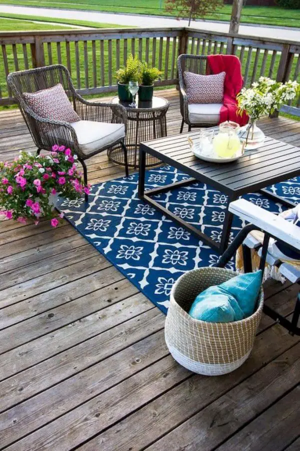 a colorful eclectic deck with a bright rug wicker and wooden furniture