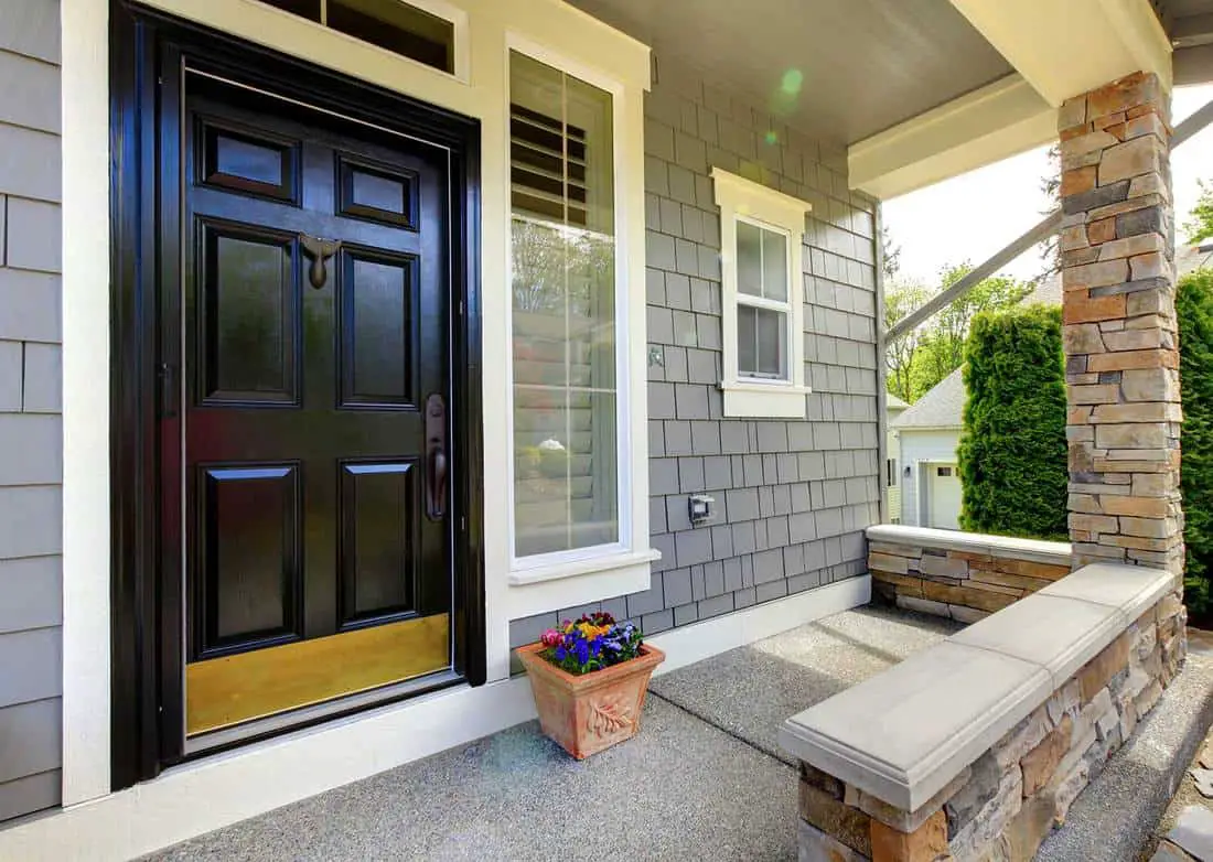 Grey house exterior with black door and stone wall