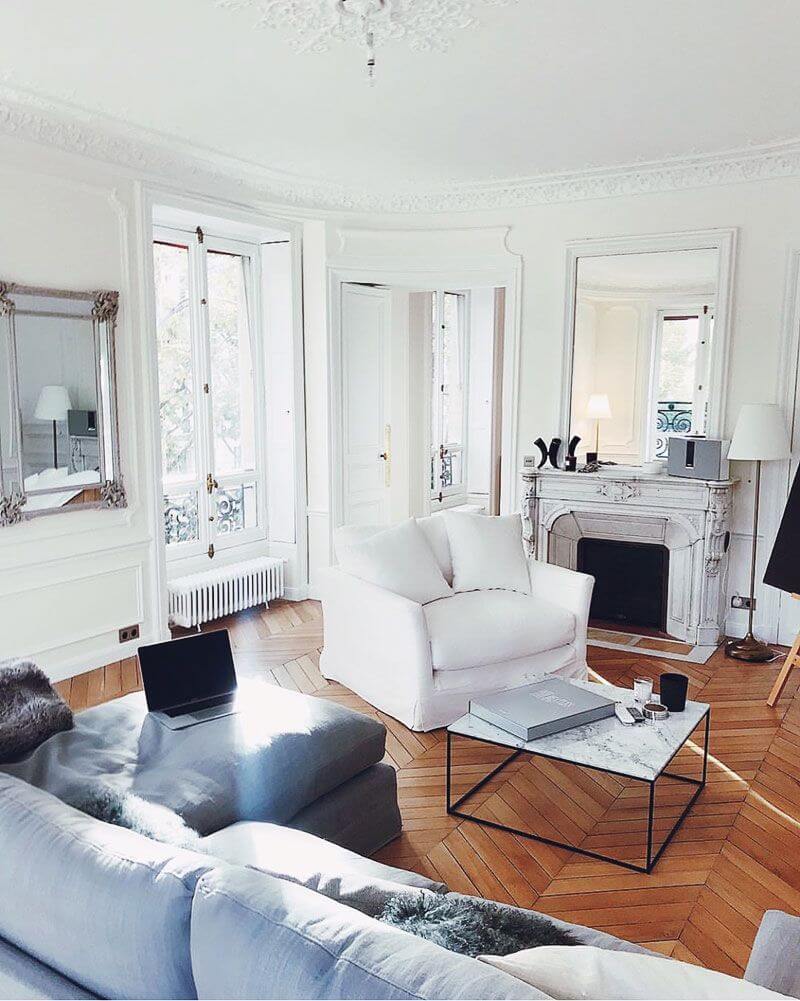Parisian living room with marble coffee table and white slipcovered accent chair