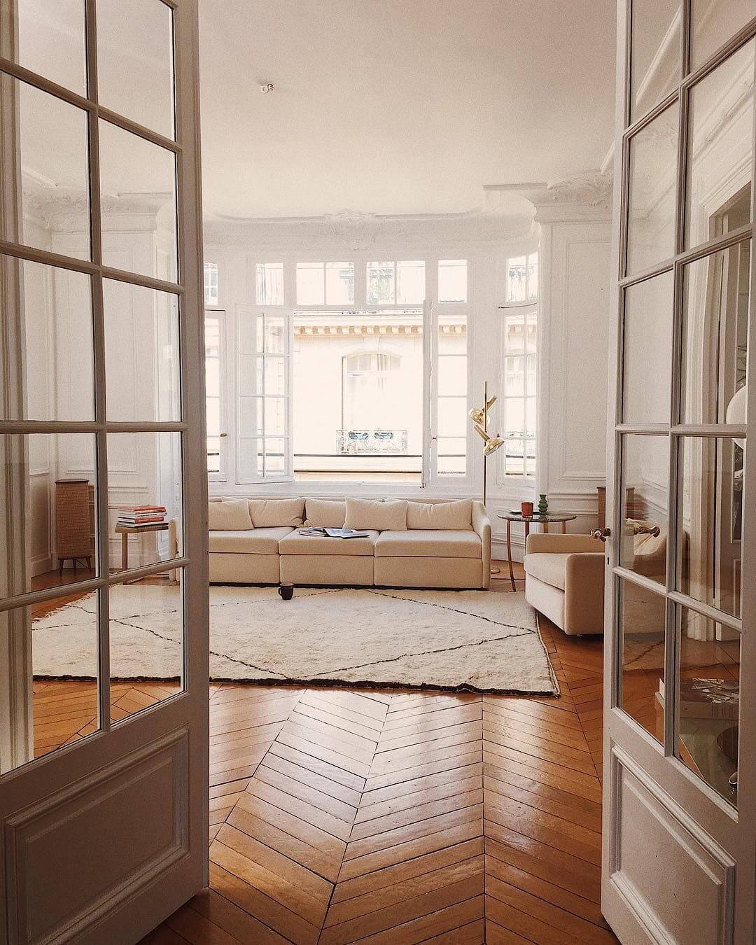 Parisian living room with beige sofa and herringbone wood floors