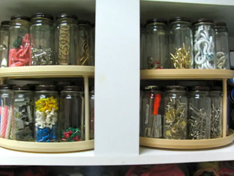 Upper cabinets with two-tiered lazy susans lined with mason jars full of small hardware in the shed. 