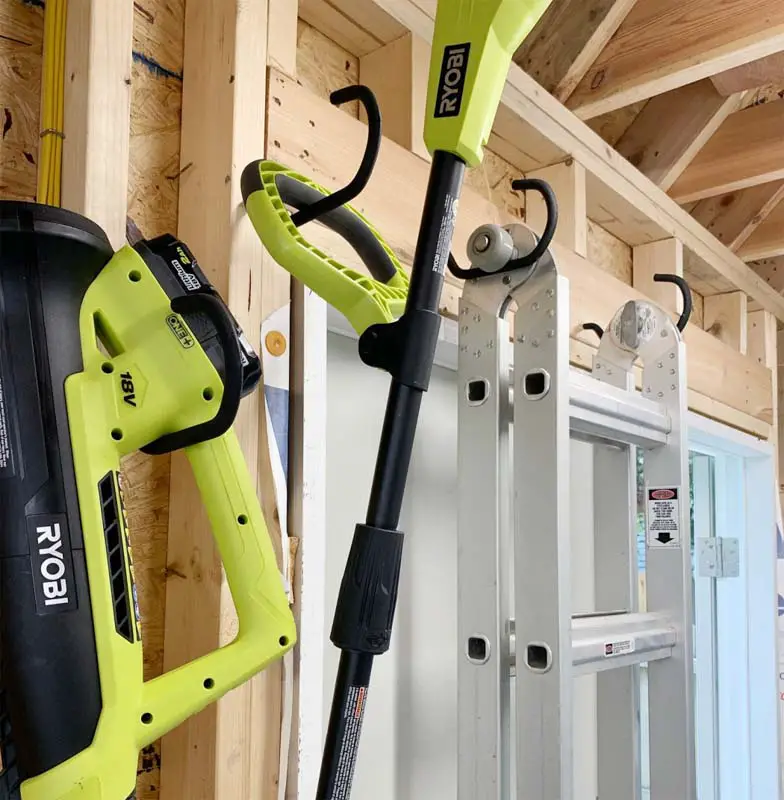 Heavy duty bike books screwed into the studs in a shed wall, with large power tools hanging. 