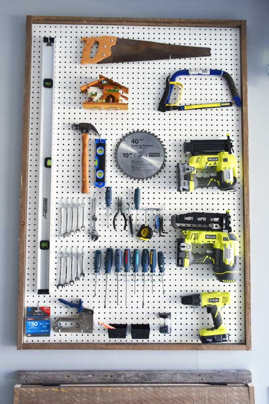 A framed sheet of pegboard storing power tools, accessories and other small tools in a shed. 