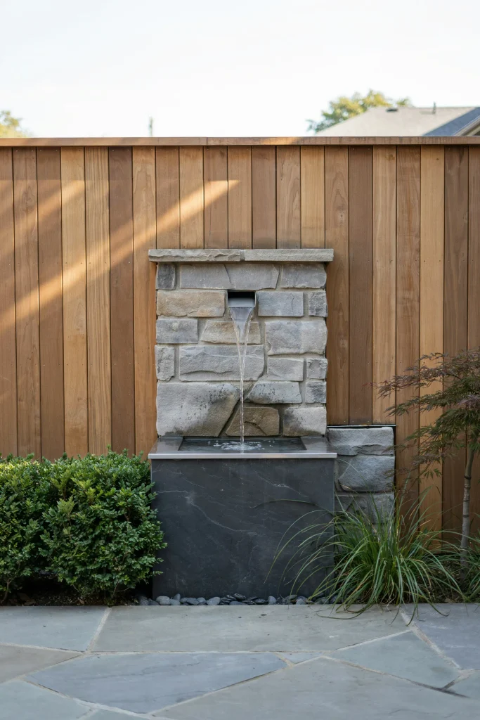 Relaxing outdoor privacy ideas with a sleek water feature built into a wooden fence