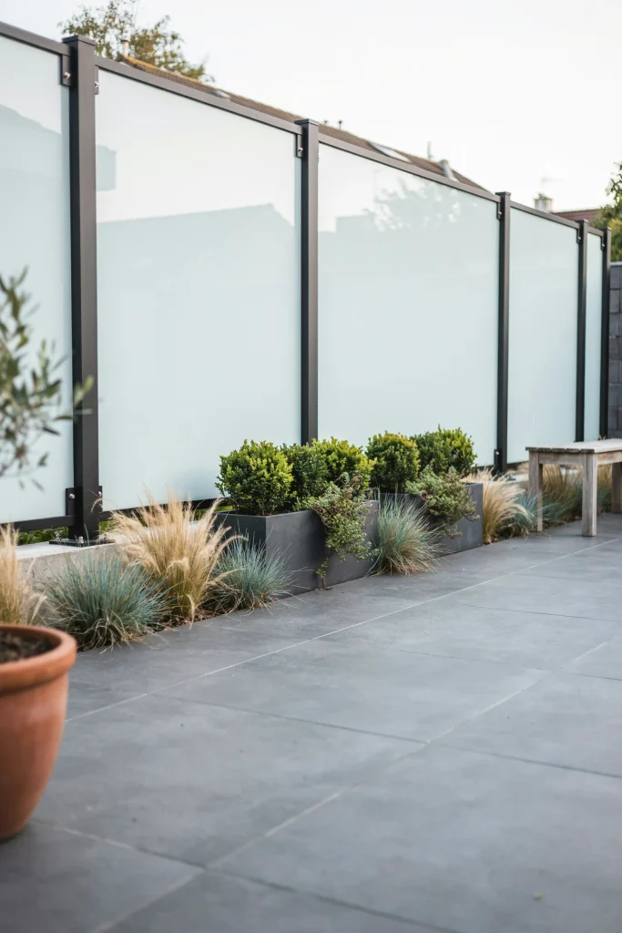 Sleek privacy fence designs using frosted glass panels for modern outdoor patios