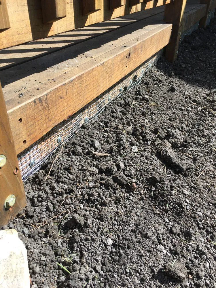 Galvanized wire mesh installed within a wood frame beneath a porch